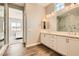 Elegant bathroom featuring marble shower, double sinks, wood flooring, and bright vanity lighting at 728 Omaggio Pl, Henderson, NV 89011