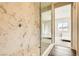 Elegant walk-in shower with marble tile and a glass door, featuring natural light at 728 Omaggio Pl, Henderson, NV 89011