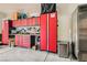 Organized garage with red cabinets, workspace, storage and stainless steel refrigerator at 728 Omaggio Pl, Henderson, NV 89011