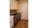 Updated laundry room featuring washer, dryer, white cabinets, and wood-look tile floor at 8224 Opal Falls St, North Las Vegas, NV 89085