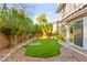 Inviting backyard with artificial grass, rock landscaping, and mature trees for privacy at 8528 Sierra Cima Ln, Las Vegas, NV 89128