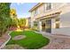 Beautiful backyard with artificial turf, mature trees, rock landscaping, and a patio at 8528 Sierra Cima Ln, Las Vegas, NV 89128