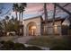 Stunning home exterior with an arched entry, manicured lawn, and elegant landscaping at dusk at 9904 Moonridge Ct, Las Vegas, NV 89134