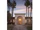 Inviting home exterior features a grand entrance with a covered archway, palm trees, and a well-manicured lawn at 9904 Moonridge Ct, Las Vegas, NV 89134
