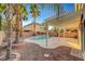Backyard features covered patio, refreshing pool, palm trees, desert landscaping, and brick accents at 10965 Ladyburn Ct, Las Vegas, NV 89141