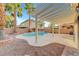 Backyard features covered patio, refreshing pool, palm trees, and desert landscaping at 10965 Ladyburn Ct, Las Vegas, NV 89141