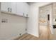 Well-lit laundry room with white cabinets, black hardware, and open doorway at 1803 Eagle Village Ave, Henderson, NV 89012