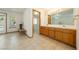 Bathroom featuring double sinks, wood cabinets, tile flooring, and doorway that connects to a bright bedroom at 2040 Tucuman Ave, Pahrump, NV 89048