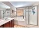 Bright bathroom featuring dual sinks, soaking tub, and glass enclosed shower offering a clean and modern aesthetic at 2853 Blythswood Sq, Henderson, NV 89044