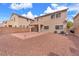 Expansive backyard featuring a stone-covered landscape, patio, and access to the covered balcony from the home's second story at 309 Gemstone Hill Ave, North Las Vegas, NV 89031