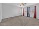 A large bedroom with neutral carpet, white walls, a ceiling fan, and natural light at 309 Gemstone Hill Ave, North Las Vegas, NV 89031