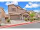 Charming stucco home featuring an attached two-car garage, a quaint front porch, and verdant landscaping at 309 Gemstone Hill Ave, North Las Vegas, NV 89031