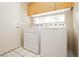 Bright laundry room with white washer and dryer, upper cabinets, and neutral tile floors at 3360 Cheltenham St, Las Vegas, NV 89129