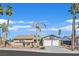 Single story home featuring desert landscaping, palm trees, and a two-car garage with a white door at 3692 Rawhide Ct, Las Vegas, NV 89120