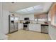 Bright kitchen featuring stainless steel appliances, white cabinetry, tile floor, and natural light from window and skylight at 3692 Rawhide Ct, Las Vegas, NV 89120