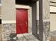 A closer view of a red front door with stone pillars and a stone facade accenting the home's entrance at 4243 Sago Lily St, Las Vegas, NV 89129