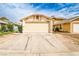 Beige single-story home featuring a two-car garage and a concrete driveway under a cloudy blue sky at 4438 Faberge Ave, Las Vegas, NV 89115