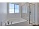 Sunlit bathroom showcasing a soaking tub next to a glass-enclosed shower with white tile at 5730 Sky Pointe Dr # 165, Las Vegas, NV 89130