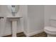 Bright bathroom with a white pedestal sink, round mirror, and modern toilet on wood-look flooring at 5730 Sky Pointe Dr # 165, Las Vegas, NV 89130
