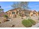 Charming home exterior with rock landscaping, desert plants, and a two car garage at 6022 Quintillion Ave, Las Vegas, NV 89122