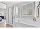 Bright bathroom with a soaking tub and a glass-enclosed shower, complemented by wood-look flooring at 69 Via Di Mello, Henderson, NV 89011