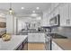 Open concept kitchen featuring stainless steel appliances, white cabinetry, central island and an adjacent living room at 69 Via Di Mello, Henderson, NV 89011