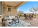 Covered patio with white sectional, outdoor dining, and views of the desert landscaping and golf course at 69 Via Di Mello, Henderson, NV 89011