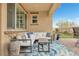 Covered patio with comfortable white sectional, blue accents, outdoor rug, and desert landscaping at 69 Via Di Mello, Henderson, NV 89011