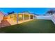 Spacious backyard with covered patio, manicured artificial grass, and decorative string lights at 7341 Girard Dr, Las Vegas, NV 89147