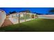 Beautiful backyard with lush artificial turf and a covered patio illuminated by charming string lights for evening gatherings at 7341 Girard Dr, Las Vegas, NV 89147