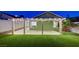 Expansive backyard features a covered patio, lush artificial turf, and ambient string lights for serene outdoor enjoyment at 7341 Girard Dr, Las Vegas, NV 89147