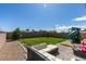 Backyard with grass, stone and a built in playset under a bright blue sky at 7712 Bandon Cliffs St, North Las Vegas, NV 89084
