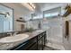 Bathroom vanity featuring dual sinks, granite countertops, and a glass-enclosed shower at 7712 Bandon Cliffs St, North Las Vegas, NV 89084