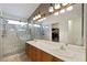 Primary bathroom featuring double sinks, wood cabinets, glass enclosed shower with marble tile, and a large mirror at 7828 Morning Flower Ln, Las Vegas, NV 89129