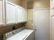 Bright laundry room with washer, dryer, white cabinets and a door to outside at 11031 Mission Lakes Ave, Las Vegas, NV 89134