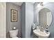 Clean half bathroom with a modern pedestal sink, a round mirror, and a framed picture at 11620 Longhirst Hall Ln, Las Vegas, NV 89138
