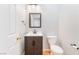 Cozy powder room with a dark wood vanity, white sink, modern fixtures, and a tiled backsplash at 11673 Pride Hill St, Las Vegas, NV 89183