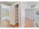 Bright hallway with wood-look floors leading to a bathroom and featuring a storage closet with wire shelving at 11673 Pride Hill St, Las Vegas, NV 89183