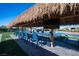 Stunning outdoor dining area with a tiki roof, large TV, a table with seating for many, and a gorgeous pool in the background at 120 Chartan Ave, Las Vegas, NV 89183