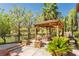Outdoor gazebo with comfortable seating and surrounding lush landscaping and a wrought iron fence at 12097 Oakland Hills Dr, Las Vegas, NV 89141