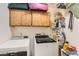 Functional laundry room with washer, dryer, overhead cabinets, and shelving for storage solutions at 209 Crosswind Way, Las Vegas, NV 89145