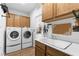 Laundry room with modern washer, dryer, sink, and ample oak cabinetry at 2606 Crested Butte St, Henderson, NV 89052