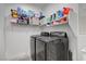This laundry room showcases modern black washer and dryer units, along with organized shelving for storage at 2669 Via Monet, Henderson, NV 89044