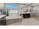 Bright bathroom featuring a soaking tub, dual vanities, and glass-enclosed shower with tile surround at 3000 Raywood Ash Dr, Las Vegas, NV 89138