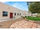 Beige home with red door, circular stone patio and well-manicured grass area at 3910 W Pebble Rd, Las Vegas, NV 89139