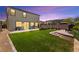Night view of a landscaped backyard with artificial turf, fire pit area, and space for outdoor activities at 4352 Browns Creek Ave, North Las Vegas, NV 89084