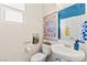 A bright half-bathroom featuring a pedestal sink, decorative wall art, and a window with blinds for natural light at 4352 Browns Creek Ave, North Las Vegas, NV 89084