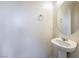 Half bath features a pedestal sink, round mirror, and stylish fixtures at 4516 Townwall St, Las Vegas, NV 89115
