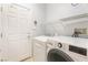 Bright laundry room featuring modern washer and dryer units with a white door at 4631 Forest Shadow Ave, Las Vegas, NV 89139