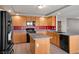 Well-lit kitchen featuring stainless steel appliances, granite countertops, an island, and wood cabinets at 506 Staghorn Pass Ave, Las Vegas, NV 89183